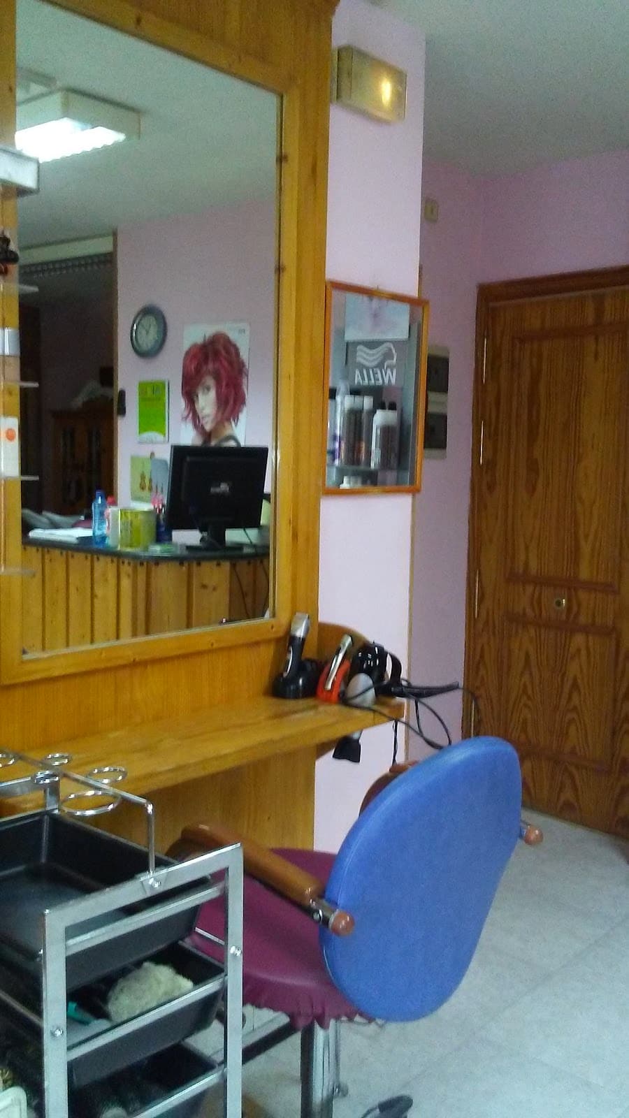 Puesto de trabajo con espejo, sillón azul y paredes rosas