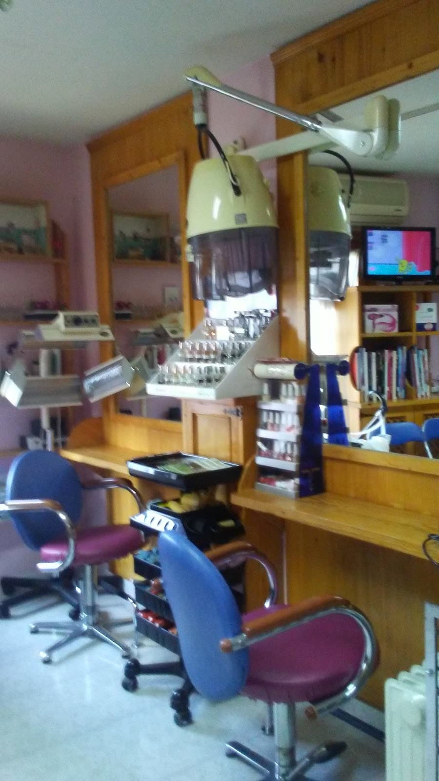 Puestos de peluquería con espejos de madera, secador de casco y sillones morados