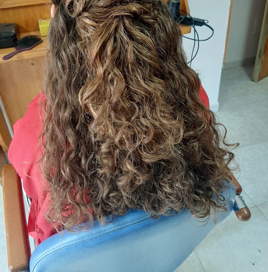 Semirrecogido con rizos naturales y una flor rosa